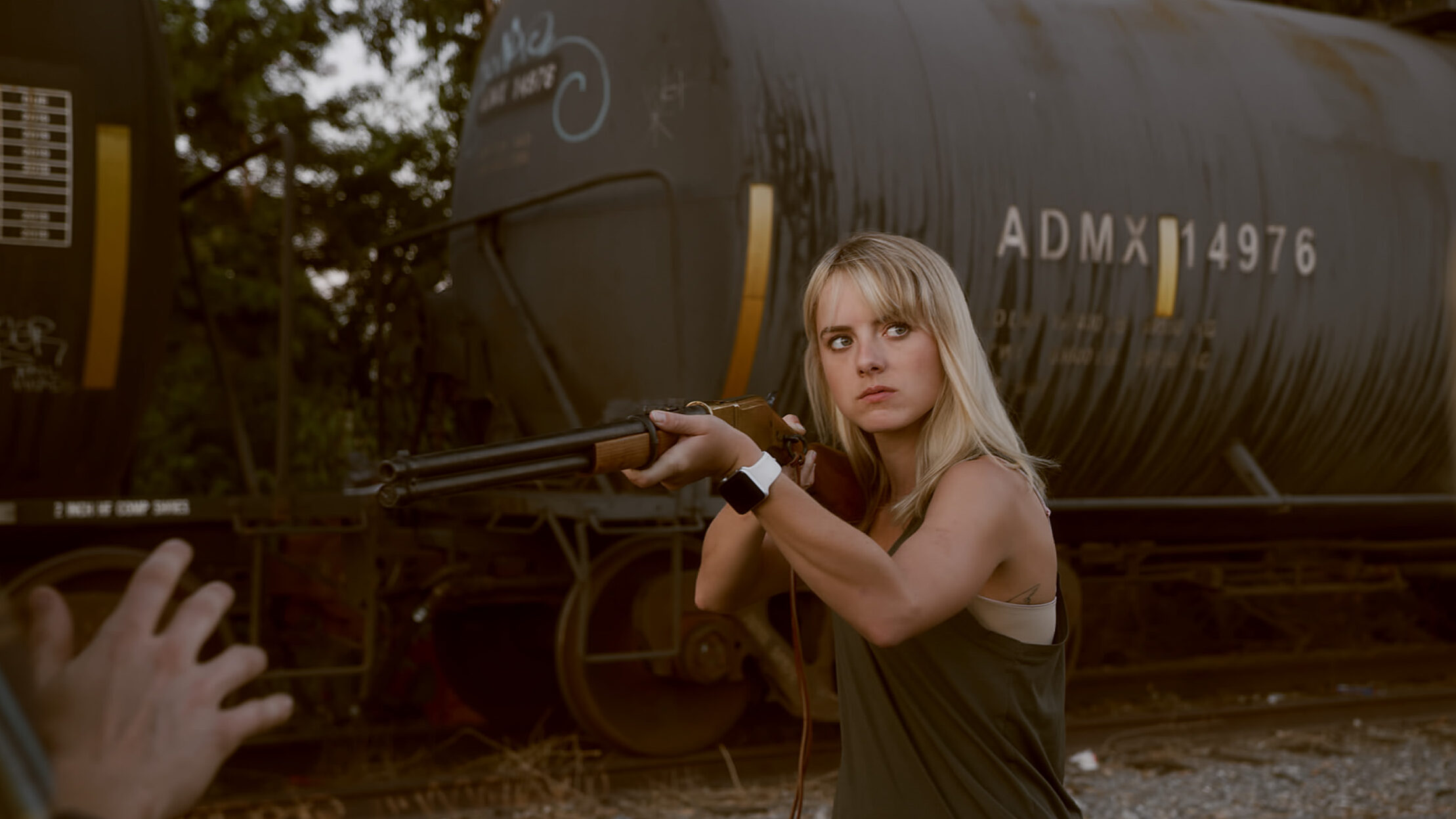 woman with a shotgun next to a train